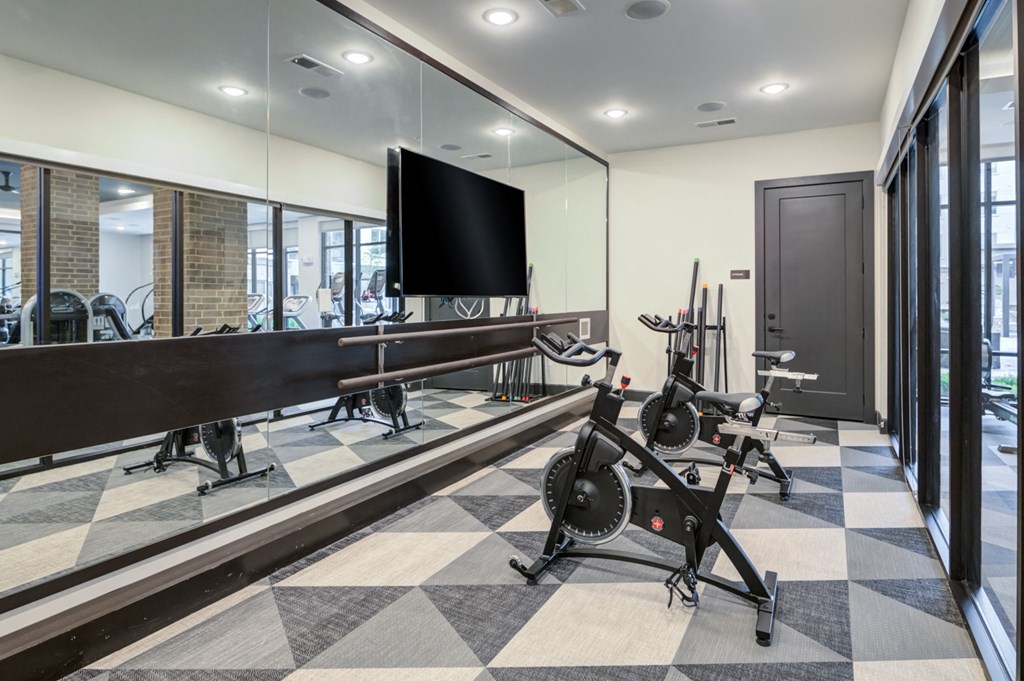 a workout room with weights and a tv on the wall and a large window
