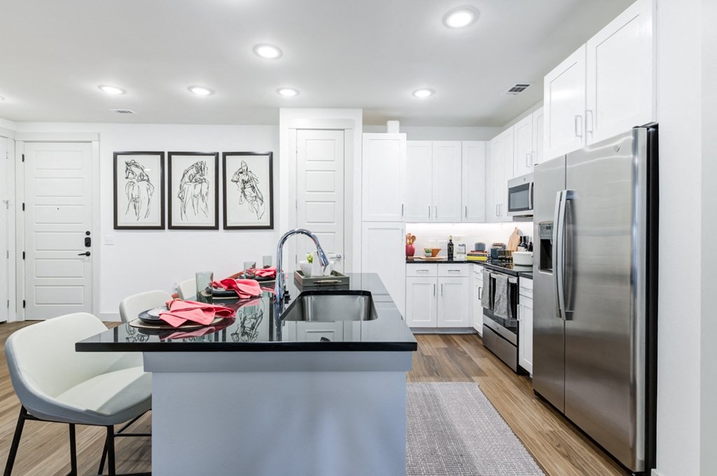 a white kitchen with stainless steel appliances and a black counter top