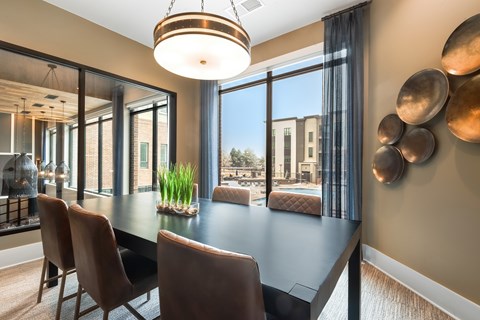 Private dining room with a dark table seating six, leather chairs, a drum chandelier, and windows over the pool.