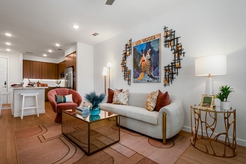 A living room with a white couch, a red chair, and a painting of a woman on the wall.