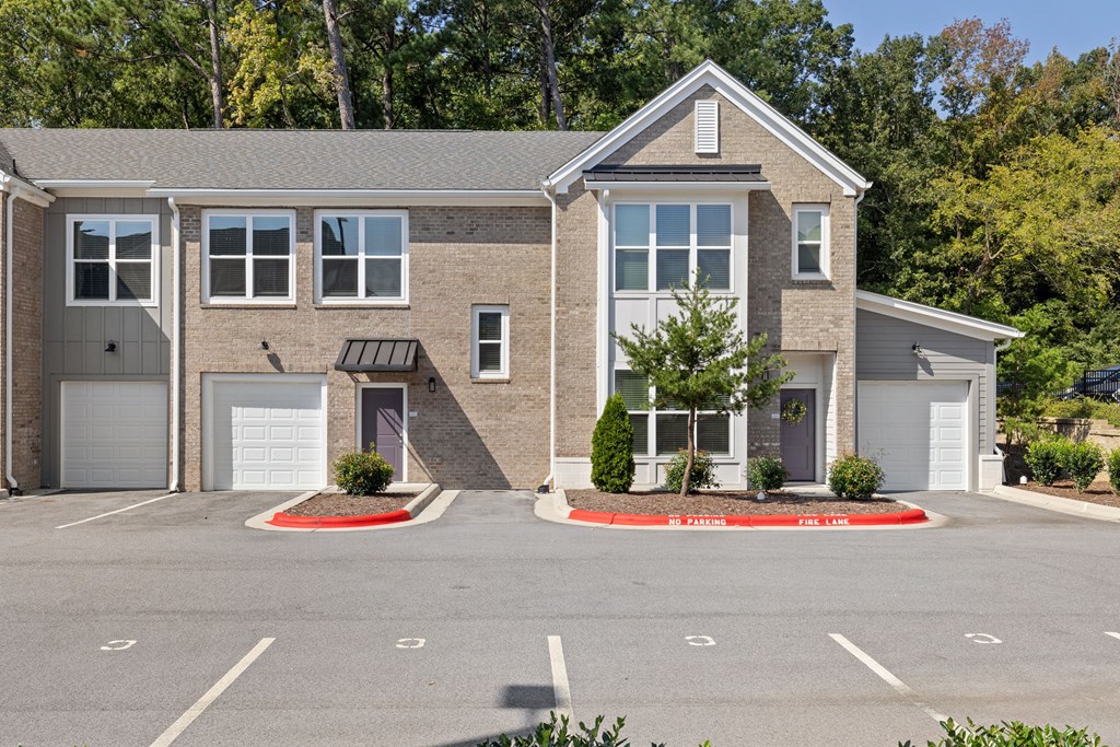A two-story building with a garage door and a driveway in front.