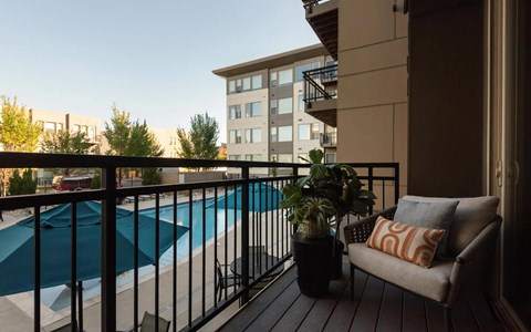 Cozy Balcony with Outdoor Seating and Views of Poolside Umbrellas