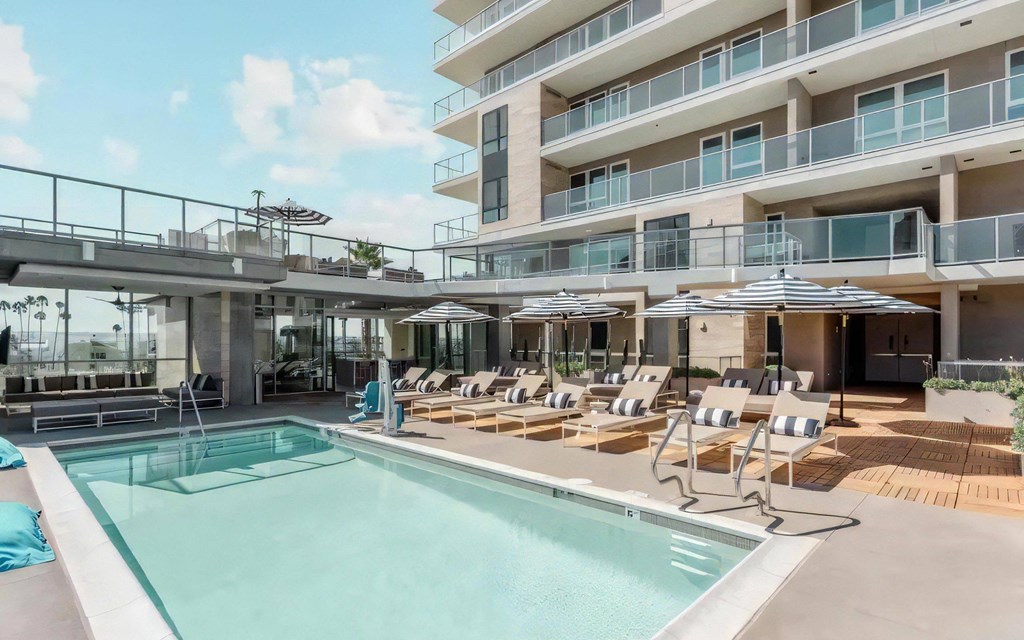 a swimming pool with chairs and umbrellas in front of a building