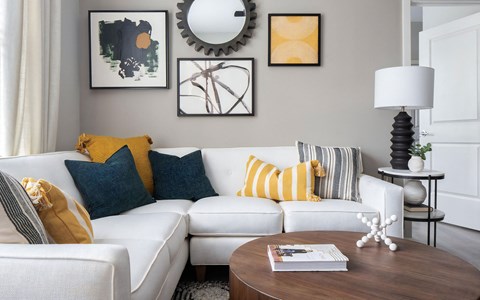 a living room with a white couch and yellow and blue pillows