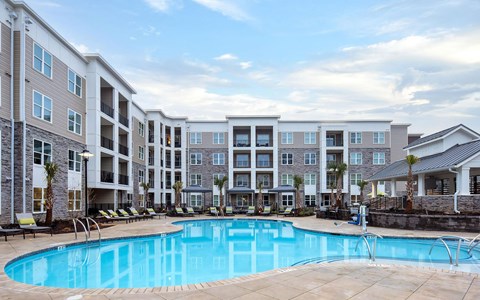 Resort-style pool at Ventura Research Park in a courtyard framed by four-storey buildings and palms and lounge chairs.