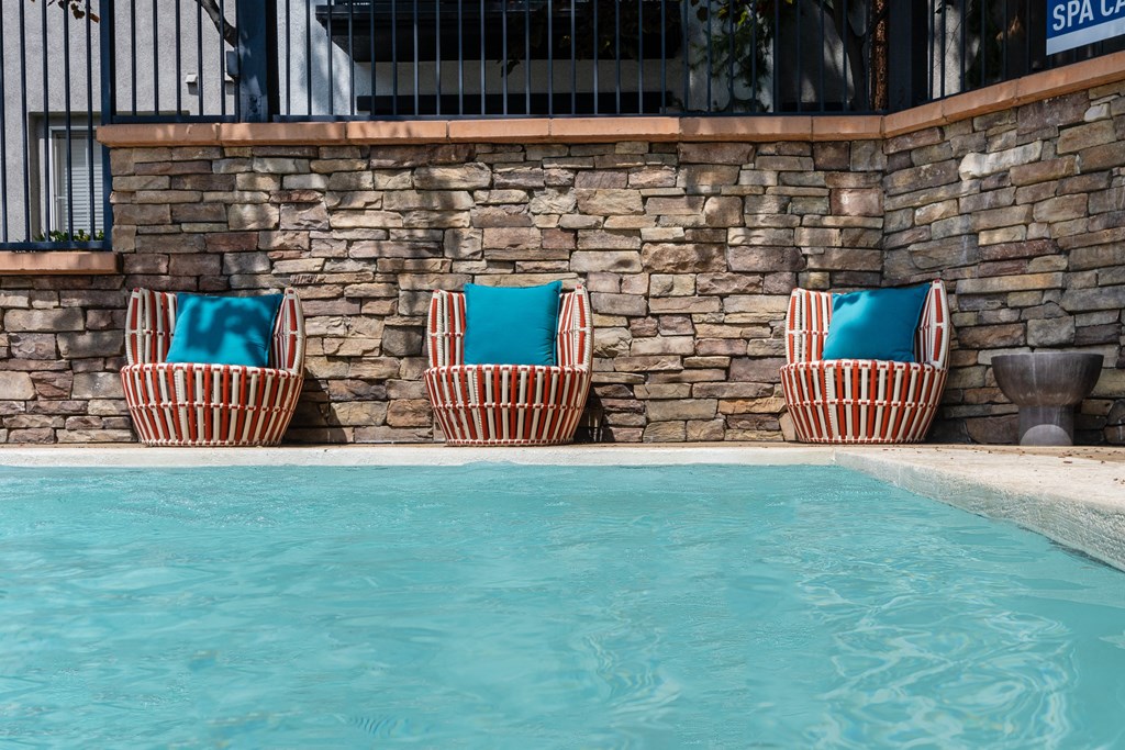 three beach chairs with blue cushions by a swimming pool