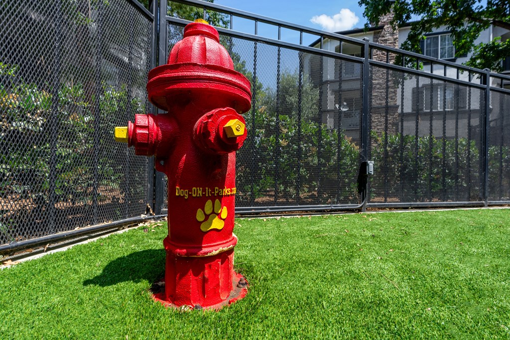 a red fire hydrant in the grass next to a fence