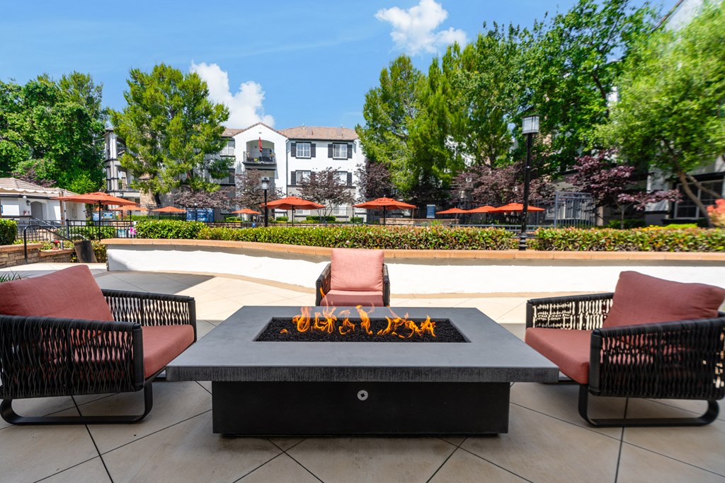 an outdoor patio with a fire pit and chairs