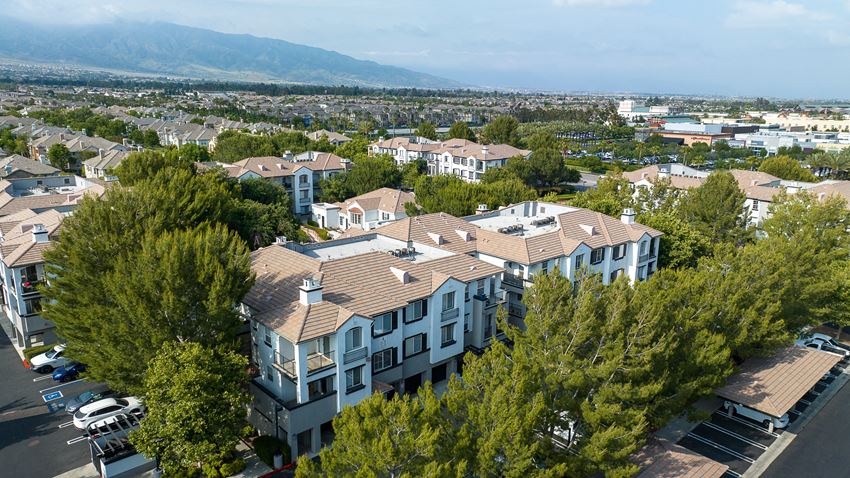 an aerial view of a row of houses with trees in the foreground and mountains in the background