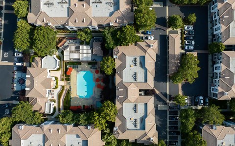 Overhead aerial of the pool courtyard with orange umbrellas, the spa and the clubhouse roofs around it surrounding it.