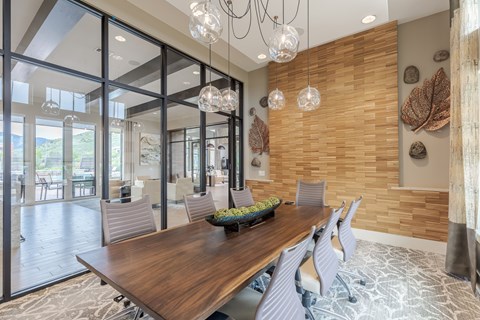 Conference room with a live-edge timber table, grey chairs, glass globe pendants and a slatted wood feature wall.