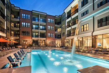 a swimming pool in front of an apartment building at night