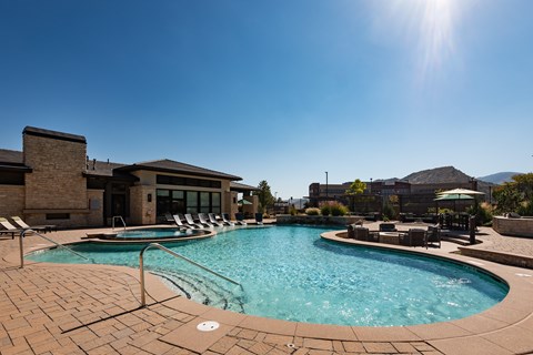 Swimming pool and adjoining spa on a paver deck at Westerly Apartments, with the clubhouse and foothills behind.