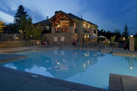 Outdoor pool at dusk with the lodge-style clubhouse and surrounding seating.