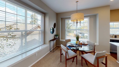 Dining area with round table, pendant light, and bay windows with built-in seating.