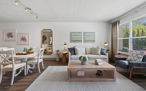 A living room with a white sofa, a coffee table, and a dining table with chairs.