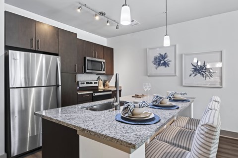 A modern kitchen with a dining table set for two.