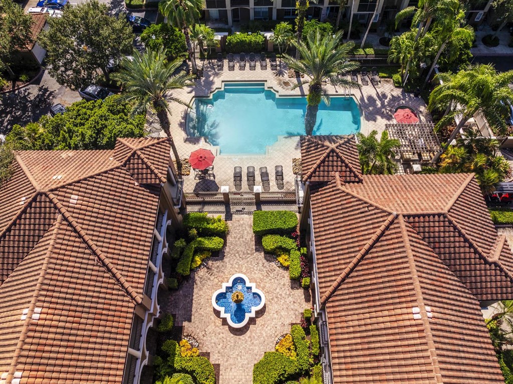 Aerial view of apartments near clubhouse with pool and landscaped greenery