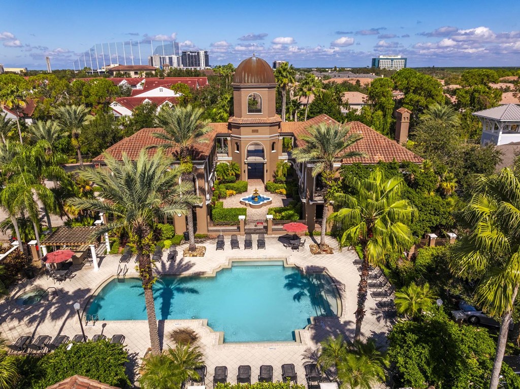 Aerial view of Mediterranean-style clubhouse with pool, palm trees, and courtyard fountain