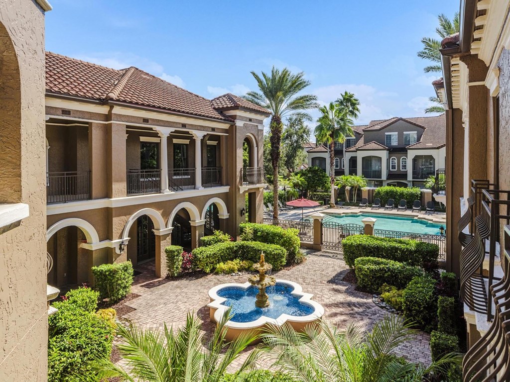 Courtyard fountain leading to the resort-style pool and palm-lined architecture.