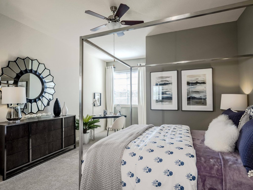Bedroom with canopy bed, dark dresser, and decorative mirror accent