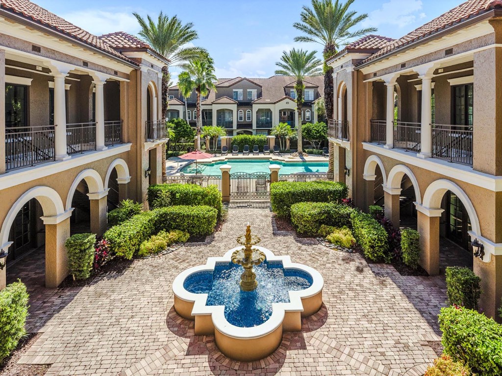 Tranquil courtyard fountain framed by palm trees and Mediterranean-style architecture.