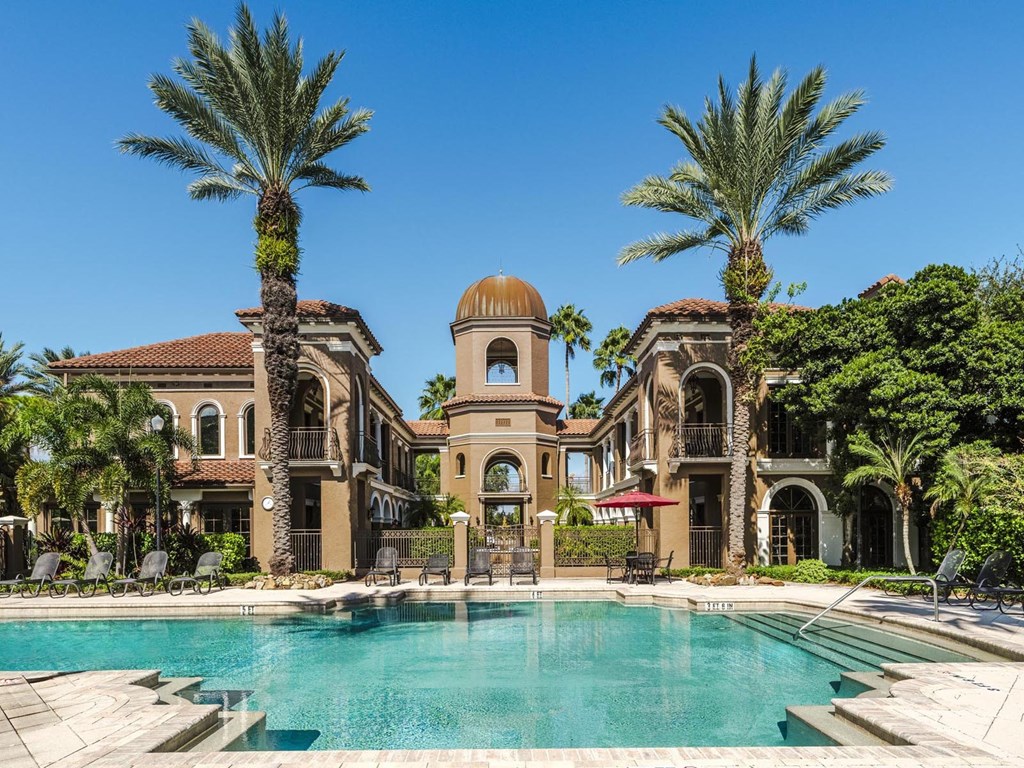 Grand pool courtyard framed by Mediterranean buildings and a central tower