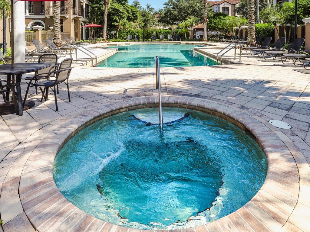 Bubbling spa beside the resort pool with lounge seating and palms