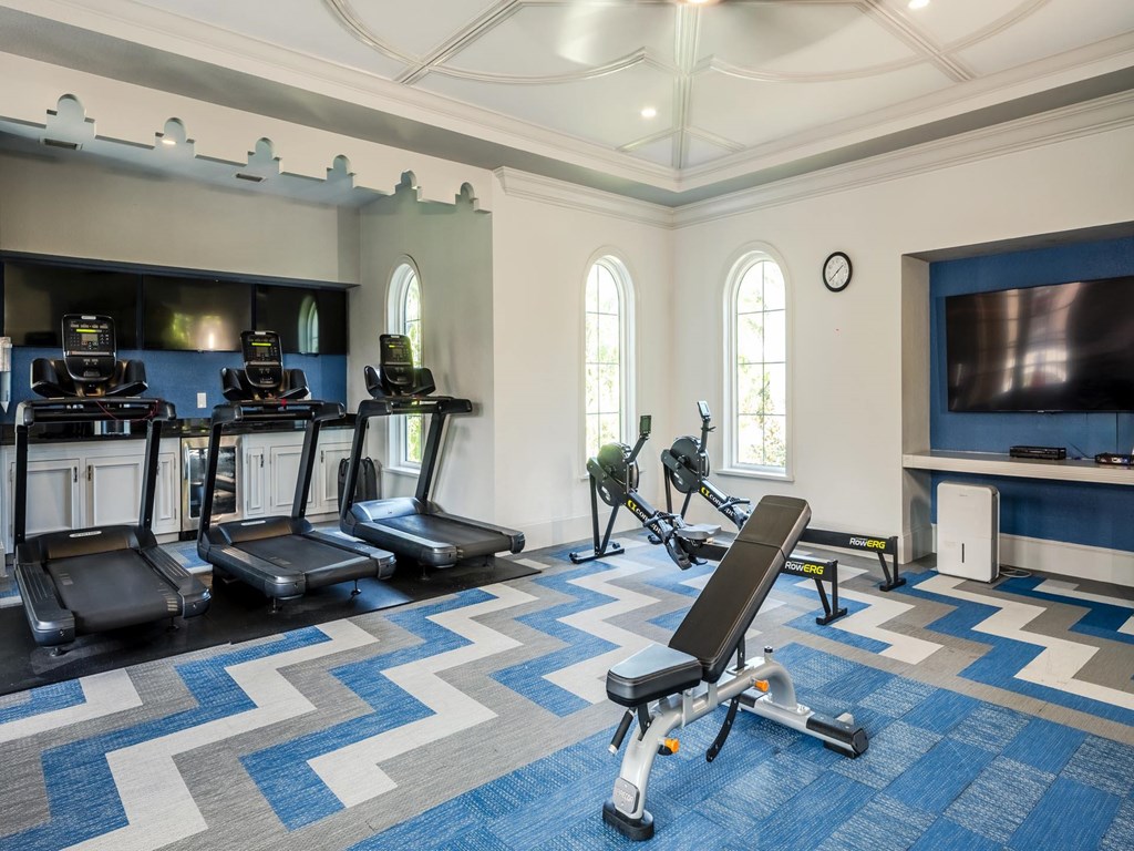 Strength training room with treadmills, rowing machines, and workout benches.