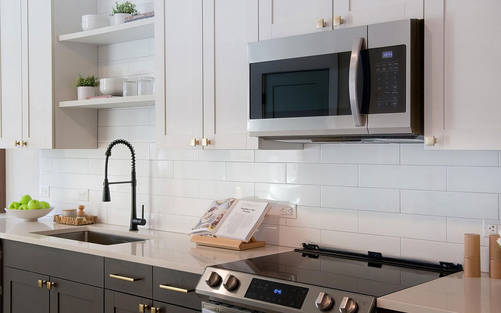 Sophisticated white countertops with subway tile backsplash and dark cabinets at Novel Cary