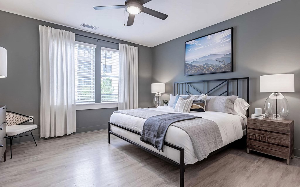 Spacious primary bedroom with dark gray walls and ceiling fan at Novel Cary
