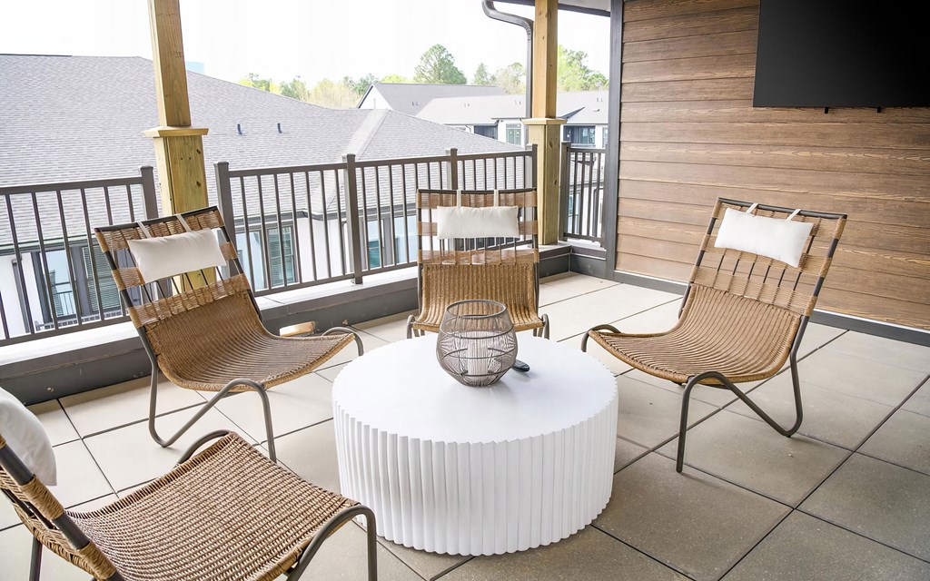 Cozy balcony with wicker style chairs and large flatscreen television at Novel Cary