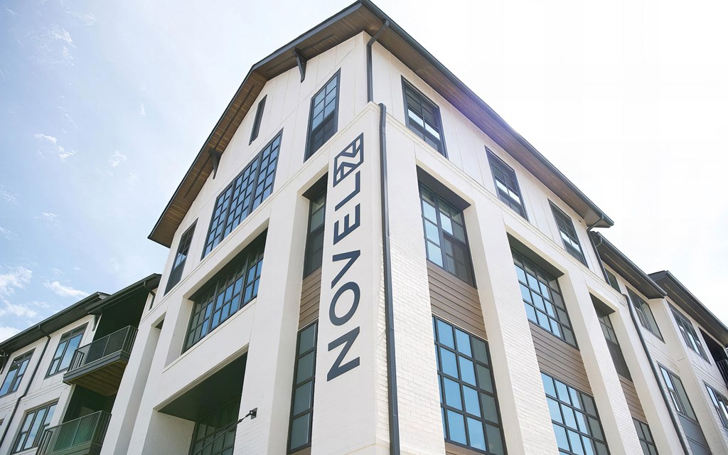 Modern apartment buildings with white bricks, wood accents, and dark window frames at Novel Cary