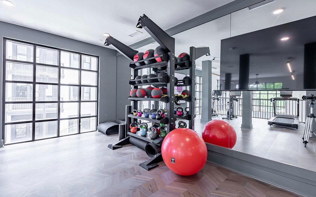 Spacious free-weight area with kettlebells, exercise balls, and floor mats at Novel Cary