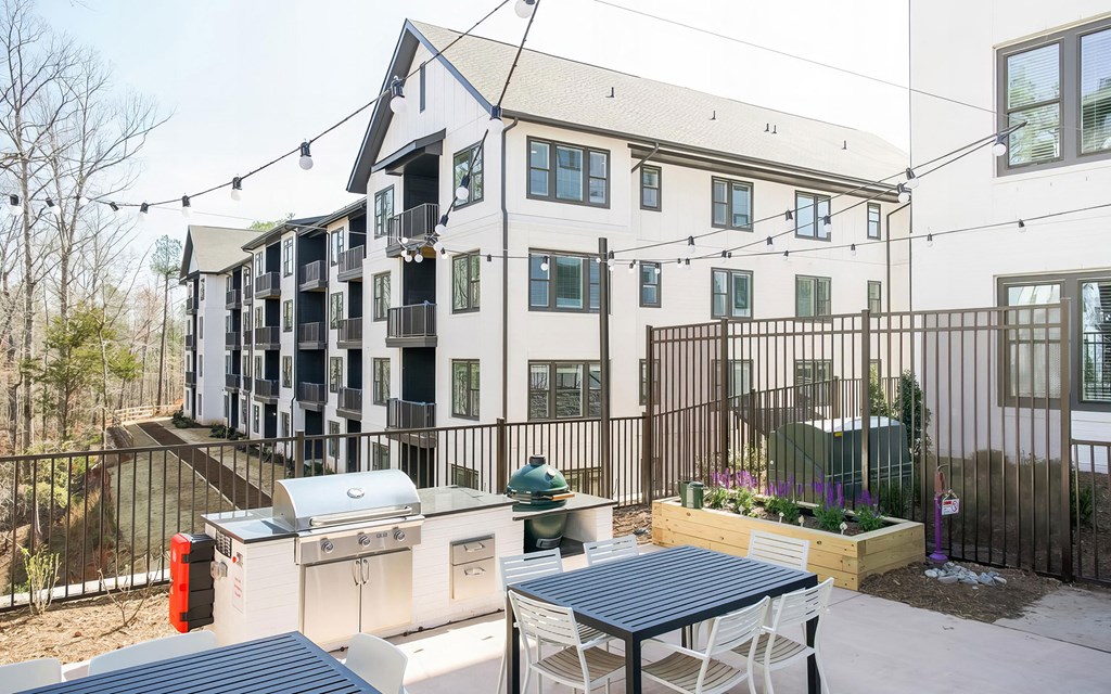 Spacious outdoor grilling station with two grills and herb planters at Novel Cary