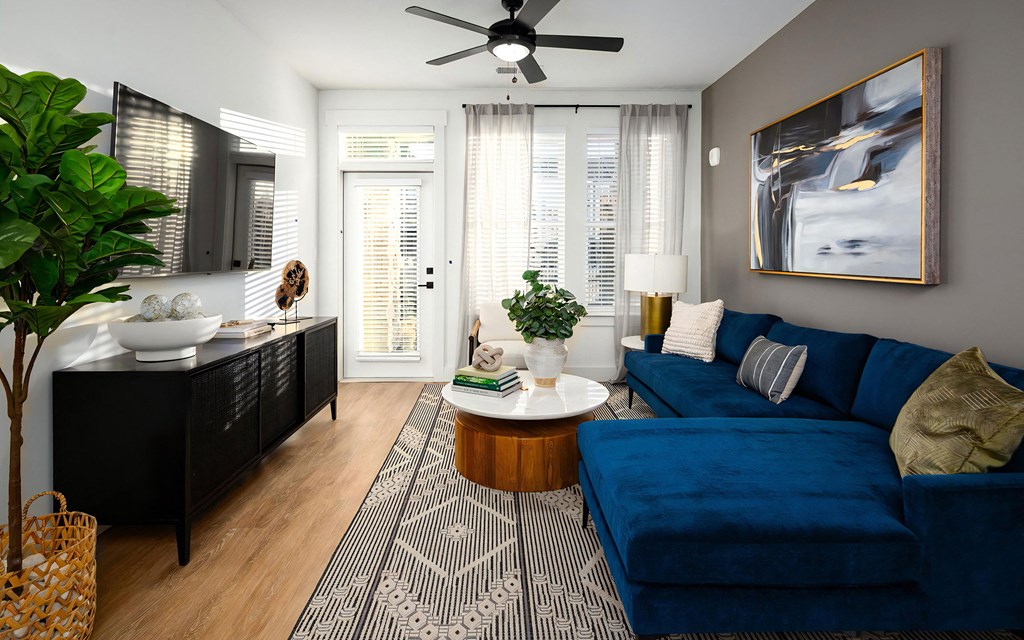 Living room with blue sectional sofa, round coffee table, and wall-mounted TV