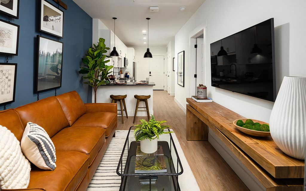 Open-concept layout with breakfast bar seating, modern lighting fixtures, and striped rug with glass coffee table