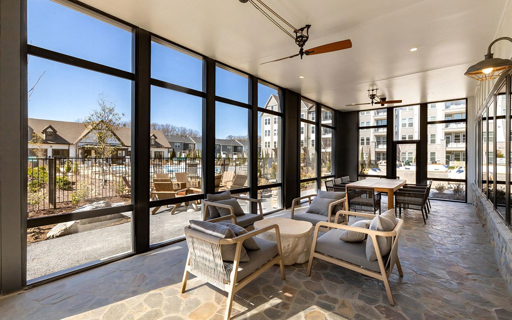 Covered Patio Lounge with Floor-to-Ceiling Windows and Cozy Seating