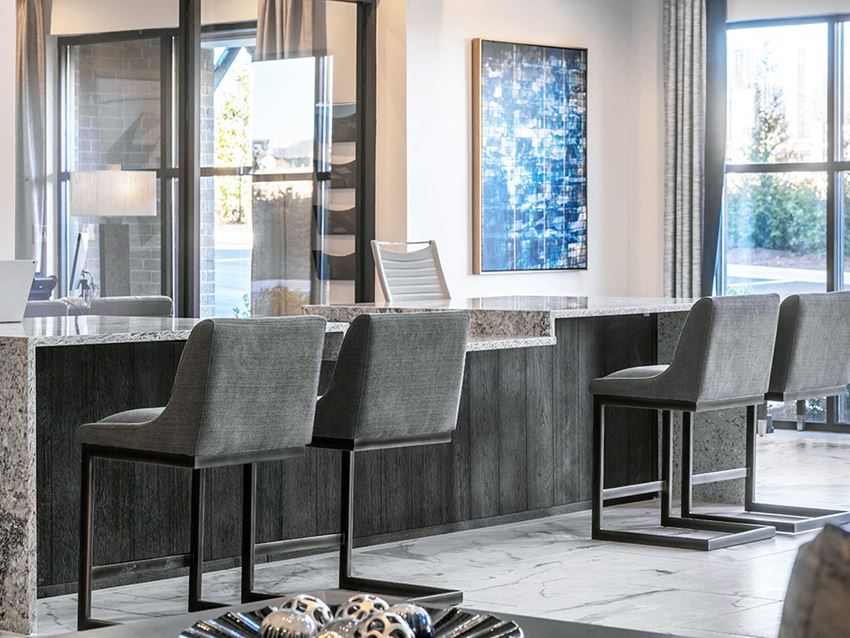 a bar with four chairs in a room with windows
