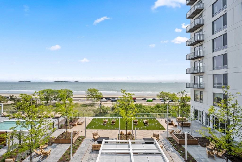 A view of a rooftop patio with a pool and a building in the background.
