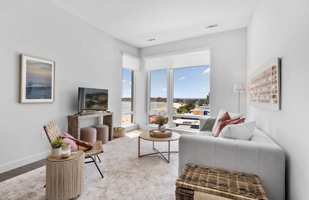 A living room with a grey couch, a wooden table, and a painting on the wall.