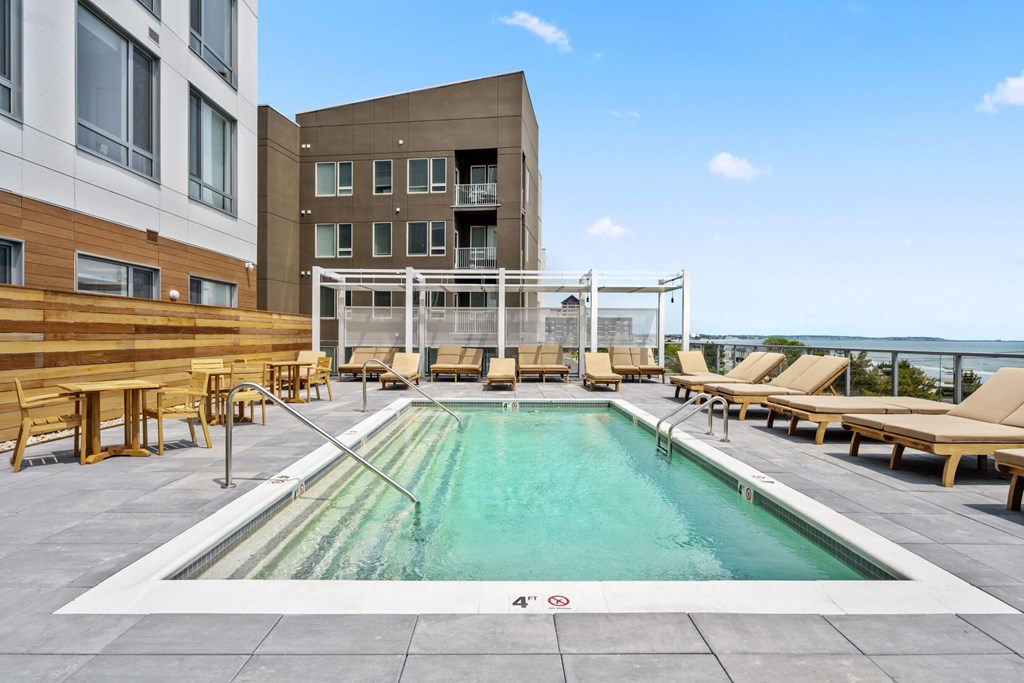 A large outdoor swimming pool with loungers and a white fence.