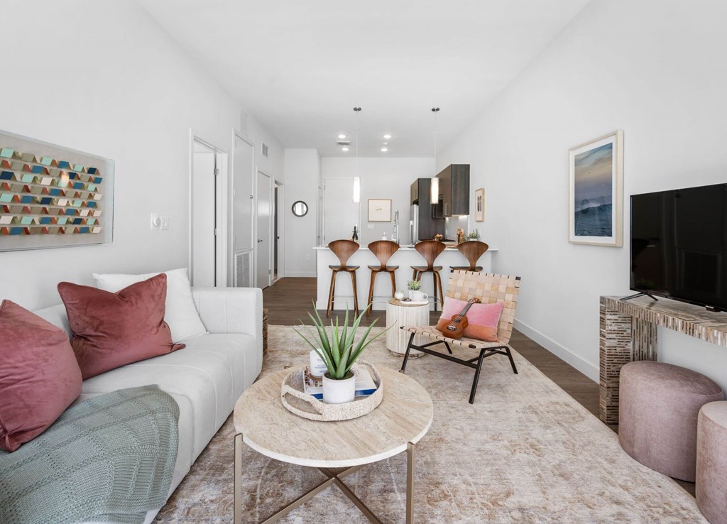 A living room with a white couch, a coffee table, and a painting on the wall.