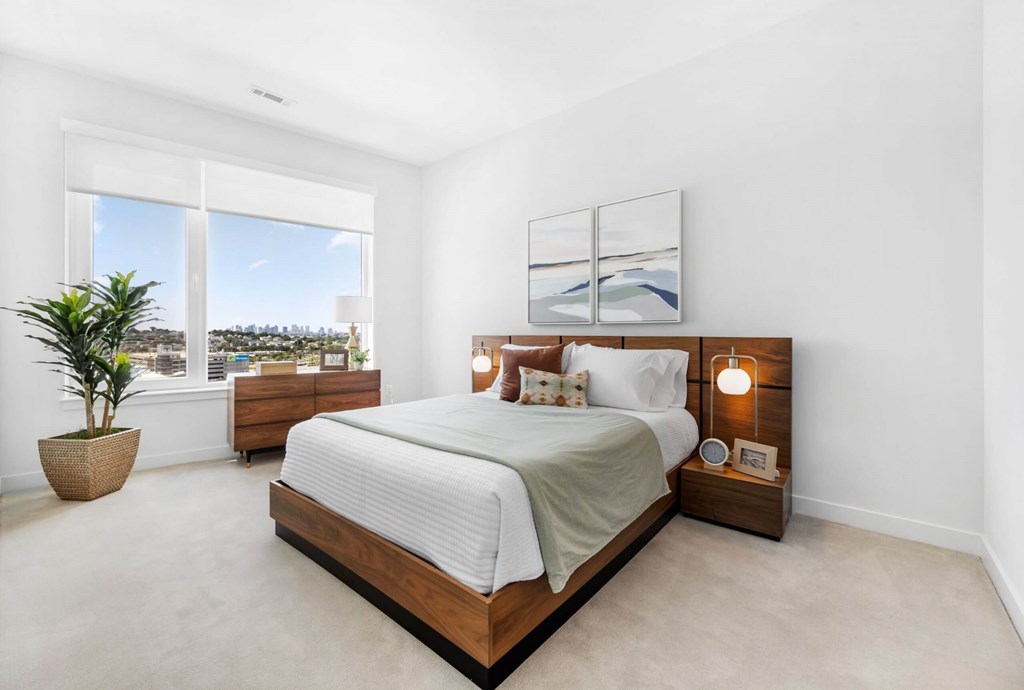 A bedroom with a large bed and a potted plant.