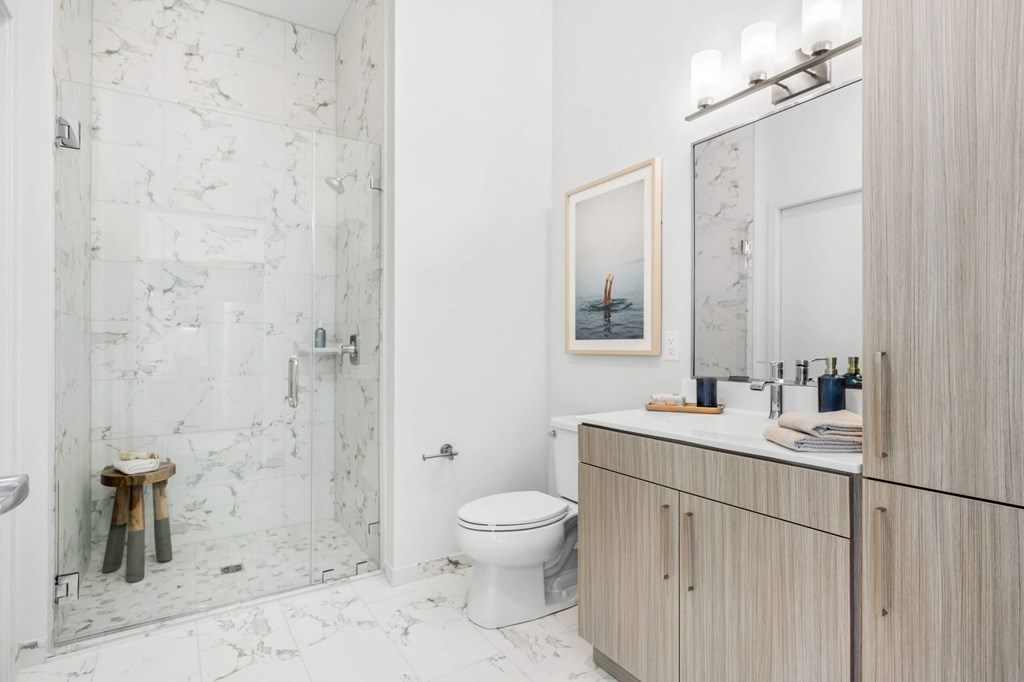 A bathroom with a toilet, sink, and a picture of a boat on the wall.