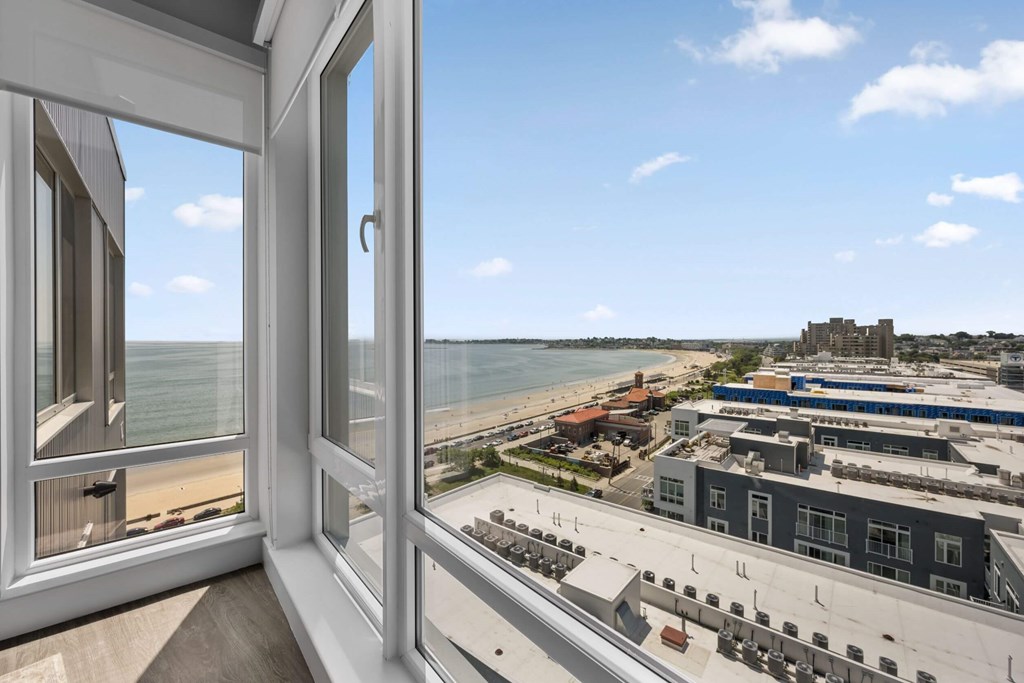 A view from a window looking out to a beach and buildings.