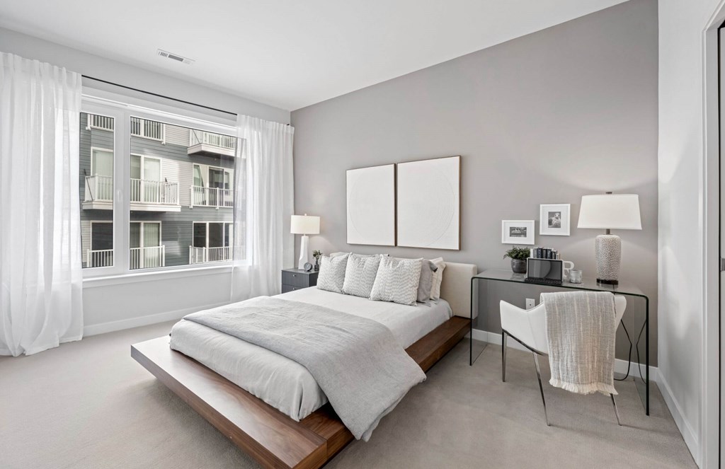 A bedroom with a large bed and a desk with a chair.