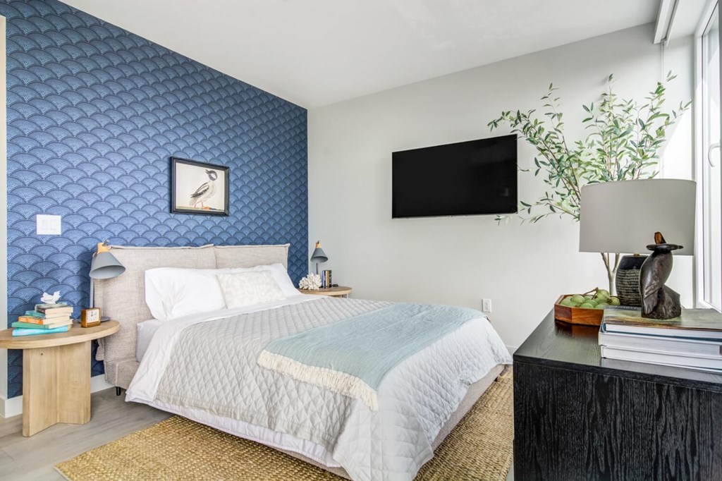 A bedroom with a bed, nightstand, and a wall clock.