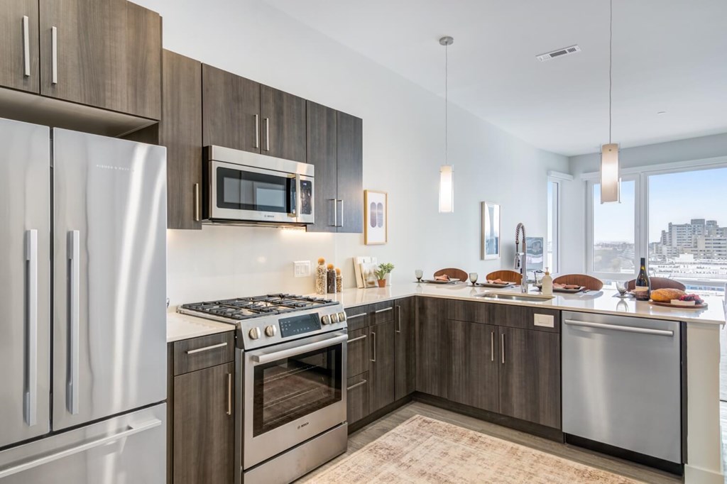 A penthouse modern kitchen with stainless steel appliances and wooden cabinets.