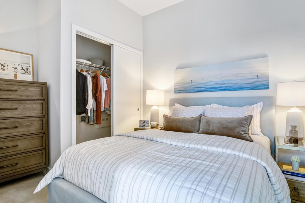 A bedroom with a large bed and a painting on the wall.